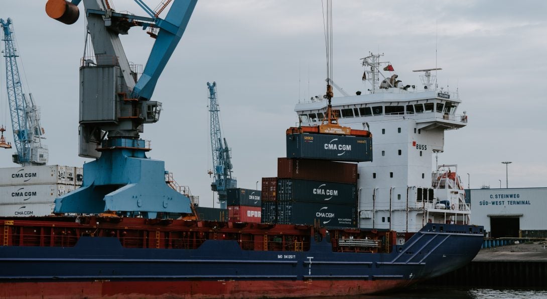 blue and red cargo ship with crane