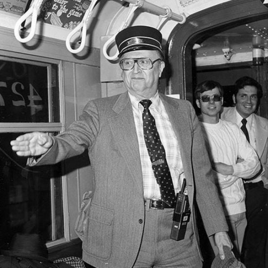 a man stands in a public transit rail car in a black and white photo