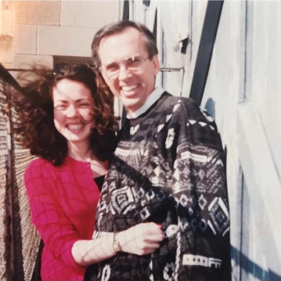 two people stand next to each other on a windy