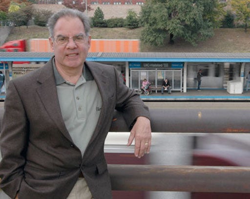 a man stands against a railing, with a CTA train station in the background