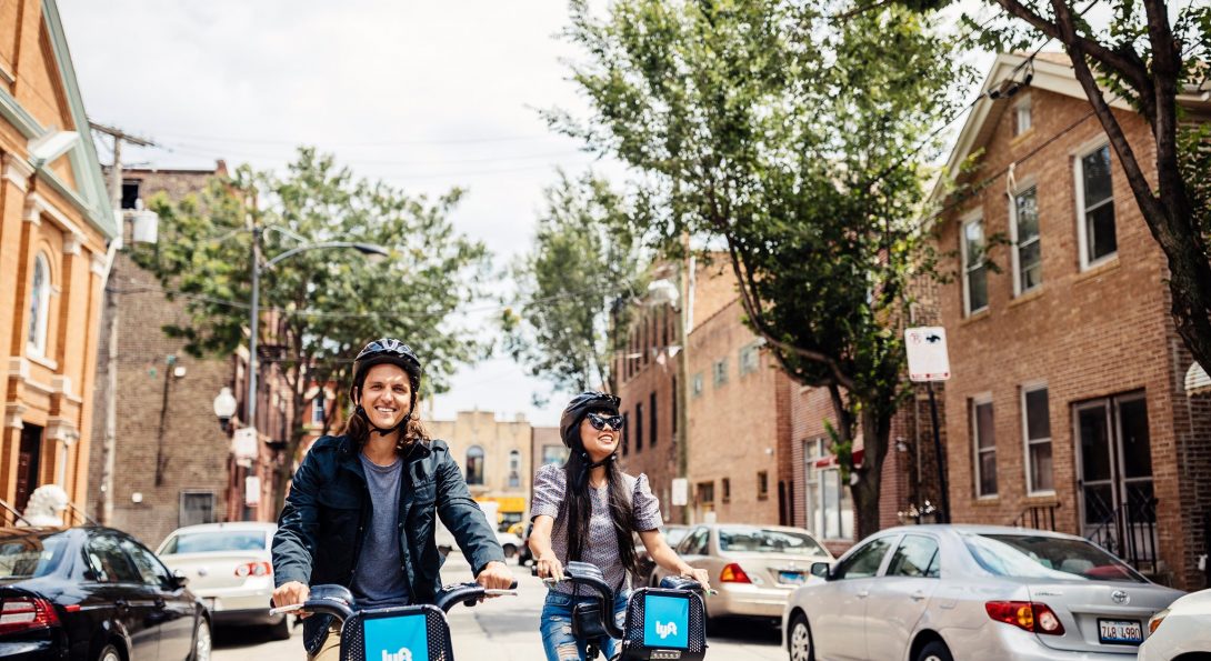 two riders with helmets on Divvy bikes in a Chicago street